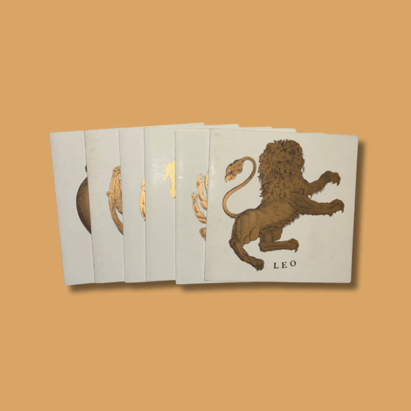 Set di biglietti d’auguri illustrati con i segni zodiacali su sfondo avorio, decorati con illustrazioni dorate; in primo piano il segno del Leone (Leo).